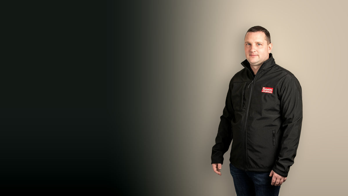 A farmer wearing the Irish Farmers Journal black soft-shell jacket, with the red Journal crest on the chest
